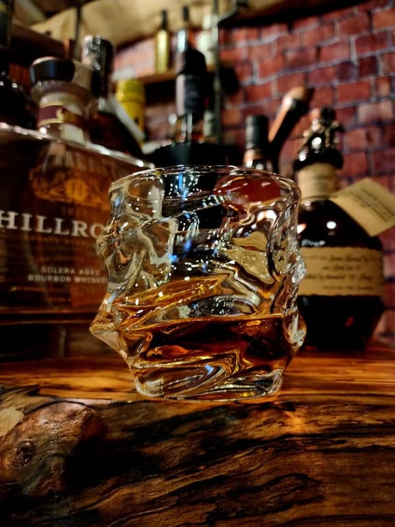 TsukiGlass Storm Crystal Whisky Glass on spalted maple bar with whisky bottles in background