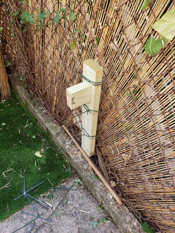 Cat-face gate propped in its opening while black strap hinges are positioned