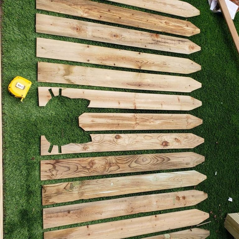 Back of the cat-face gate panel with evenly spaced pickets fastened across horizontal wood rails