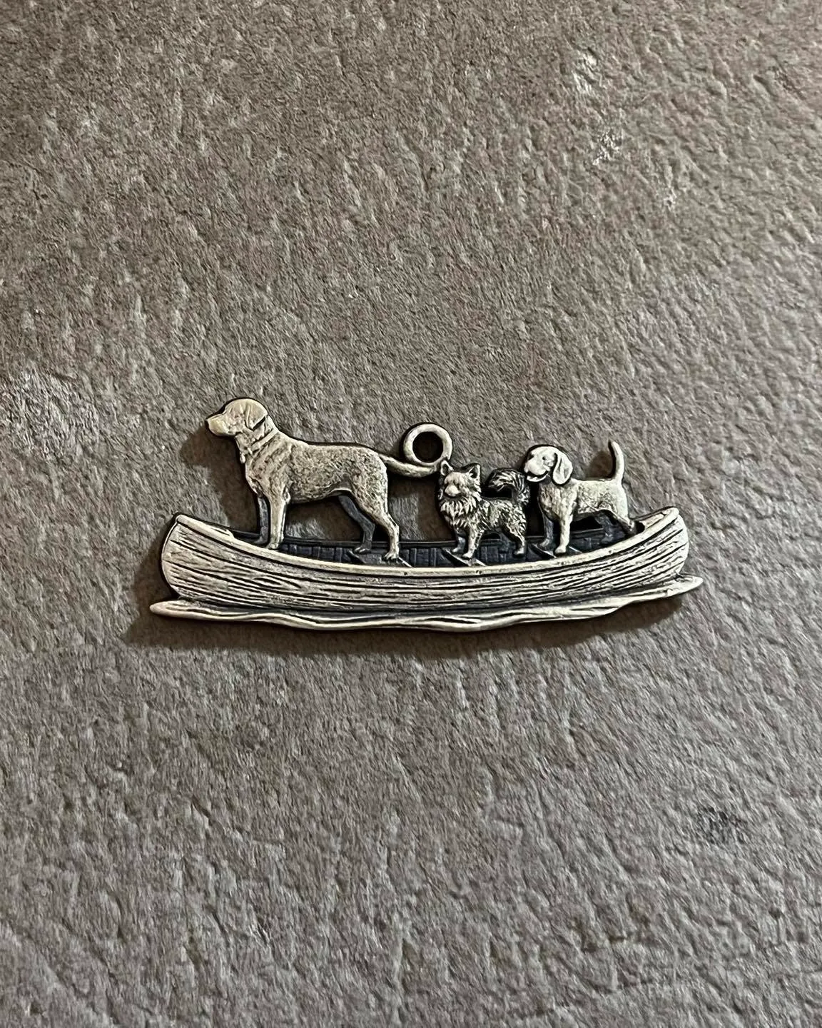 Christopher Frank's finished laser engraved pendant showing three dogs standing in a small boat.