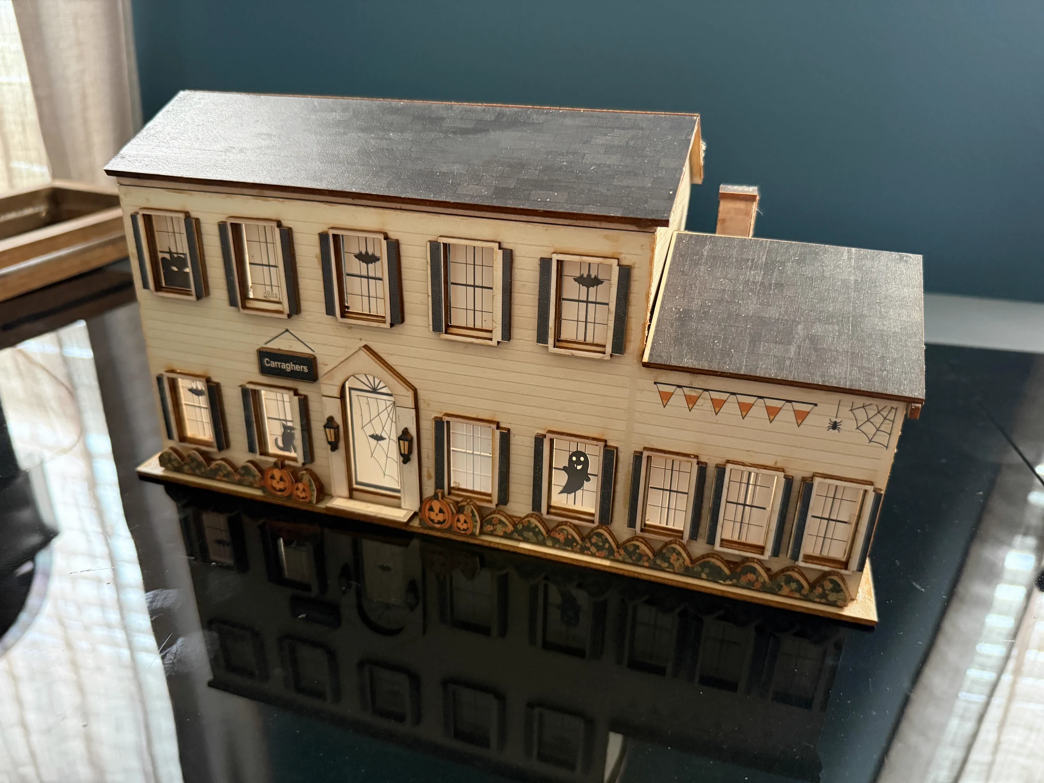 Our miniature home with layered basswood shutters, porch lamps and a seasonal pumpkin display